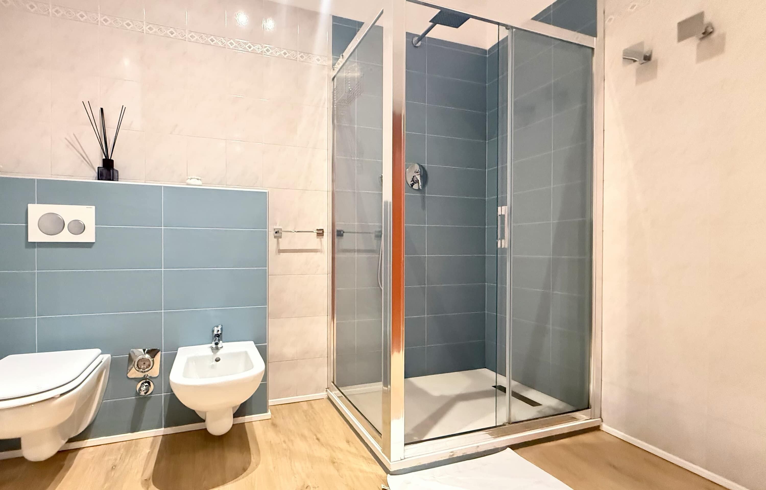 Un bagno con WC, bidet e cabina doccia in vetro.