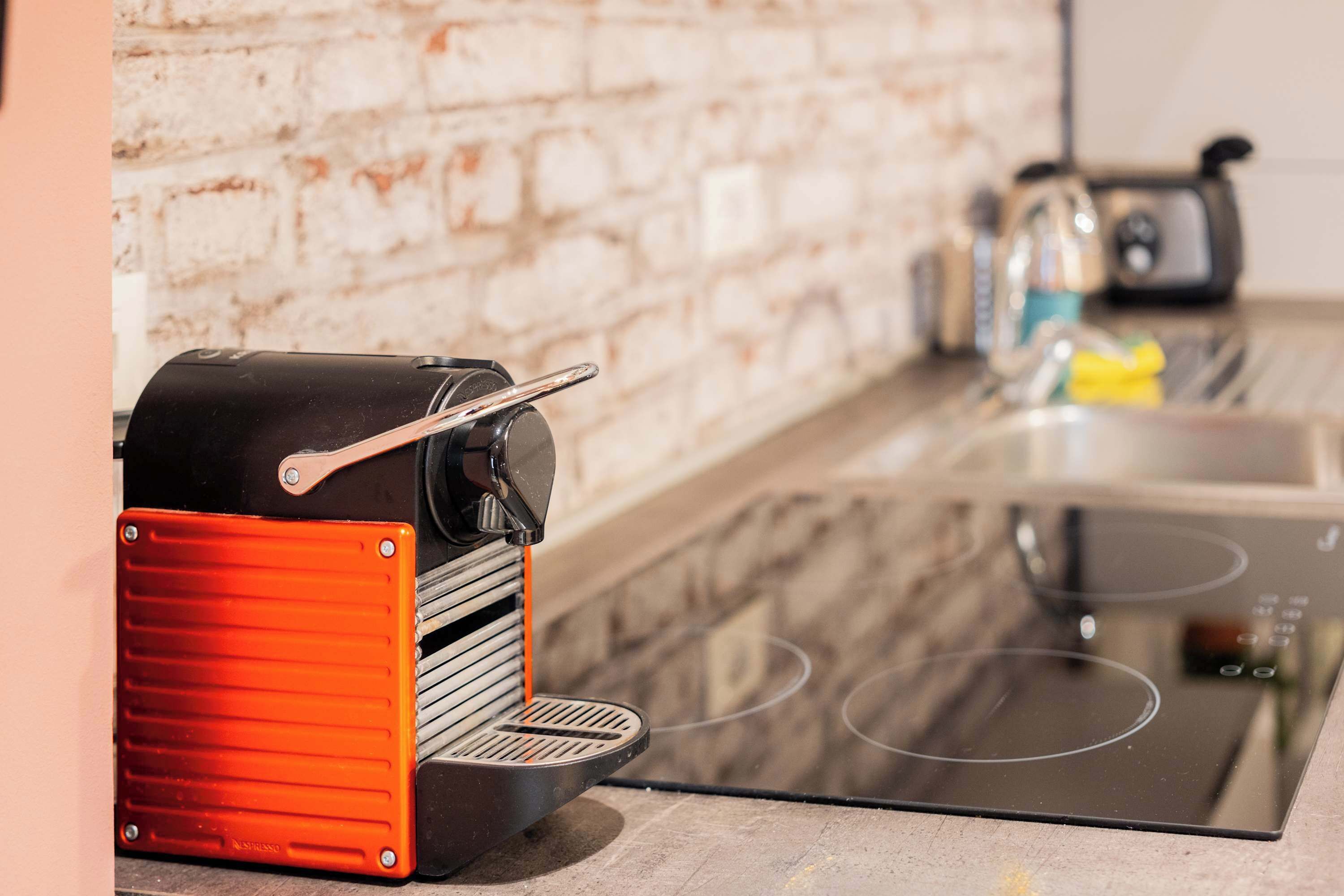 A kitchen with a modern espresso machine, a toaster, and a stovetop.