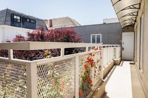 A narrow corridor with a white fence, red flowering plants, and a door at the end. - Studio Oasis | Near Bellavista and Hospitals (Providencia)