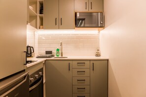 A compact kitchen with a microwave, oven, and a coffee maker. - Studio Oasis | Near Bellavista and Hospitals (Providencia)