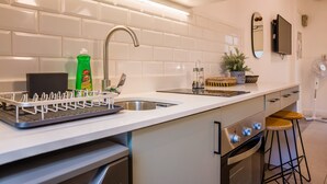 A modern kitchen with a white tiled backsplash, stainless steel sink, and a built-in oven. - Stylish Studio in Bellavista with Great Amenities (Providencia)