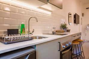 Een moderne keuken met een witte betegelde achterwand, een roestvrijstalen spoelbak en een inbouwoven.