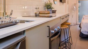 A modern kitchen with a built-in oven, a stainless steel sink, and a white countertop. - Stylish Studio in Bellavista with Great Amenities (Providencia)
