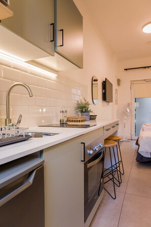 Een moderne keuken met een inbouwoven, een roestvrijstalen spoelbak en een wit aanrecht.
