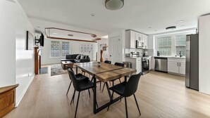 Una cocina moderna con comedor, suelo de madera y armarios blancos.
