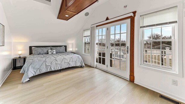Un dormitorio con una cama, una mesita de noche, una ventana y una puerta que da a un balcón.
