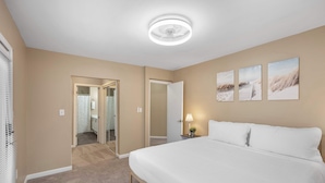 Ein Hotelzimmer mit einem großen Bett, einem Deckenventilator und drei an der Wand befestigten Bildern.