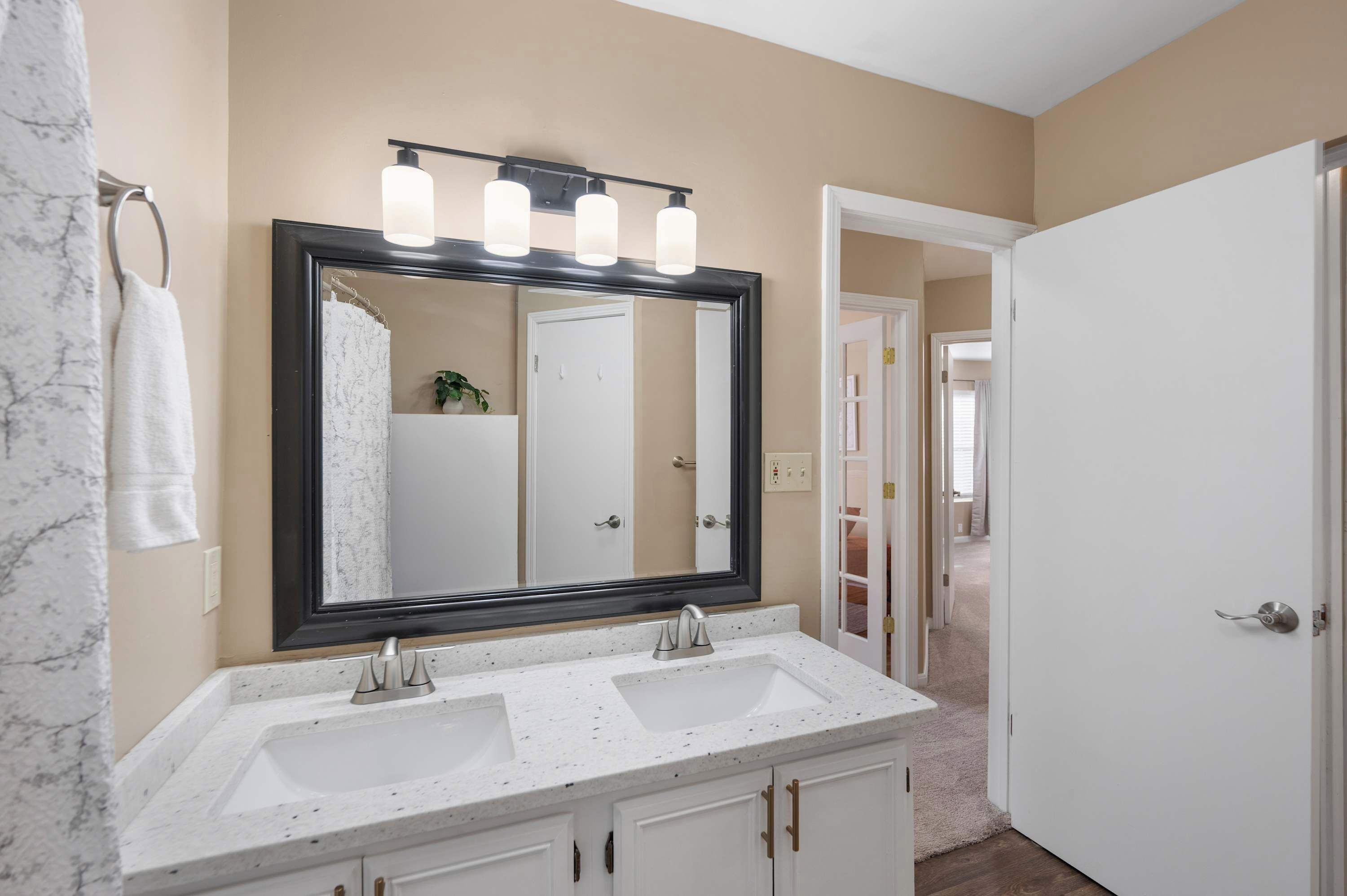 Une salle de bain avec un grand miroir, deux lavabos et un porte-serviettes.