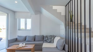 Un salon moderne avec un canapé gris, une table basse en bois et un escalier doté de rampes noires.
