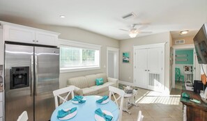A modern kitchen with a stainless steel refrigerator, a dining table set with plates and napkins, and a ceiling fan. - Coconut cottage unit 2! (Holmes Beach)