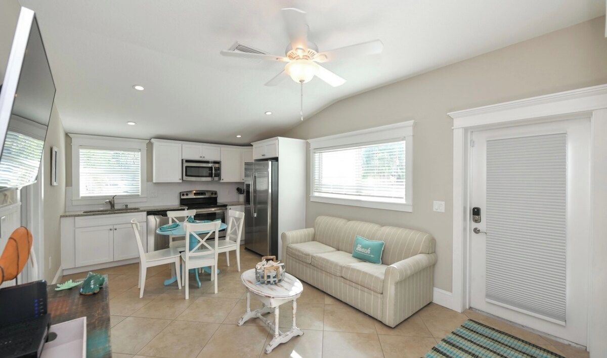 A compact living space with a kitchenette, a dining area, a sofa, and a ceiling fan.
