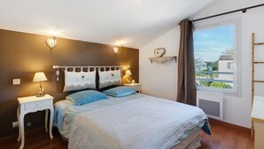Ein Schlafzimmer mit einem Bett, Nachttischen, Wandleuchten, einem Fenster mit Blick und einer Heizung.
