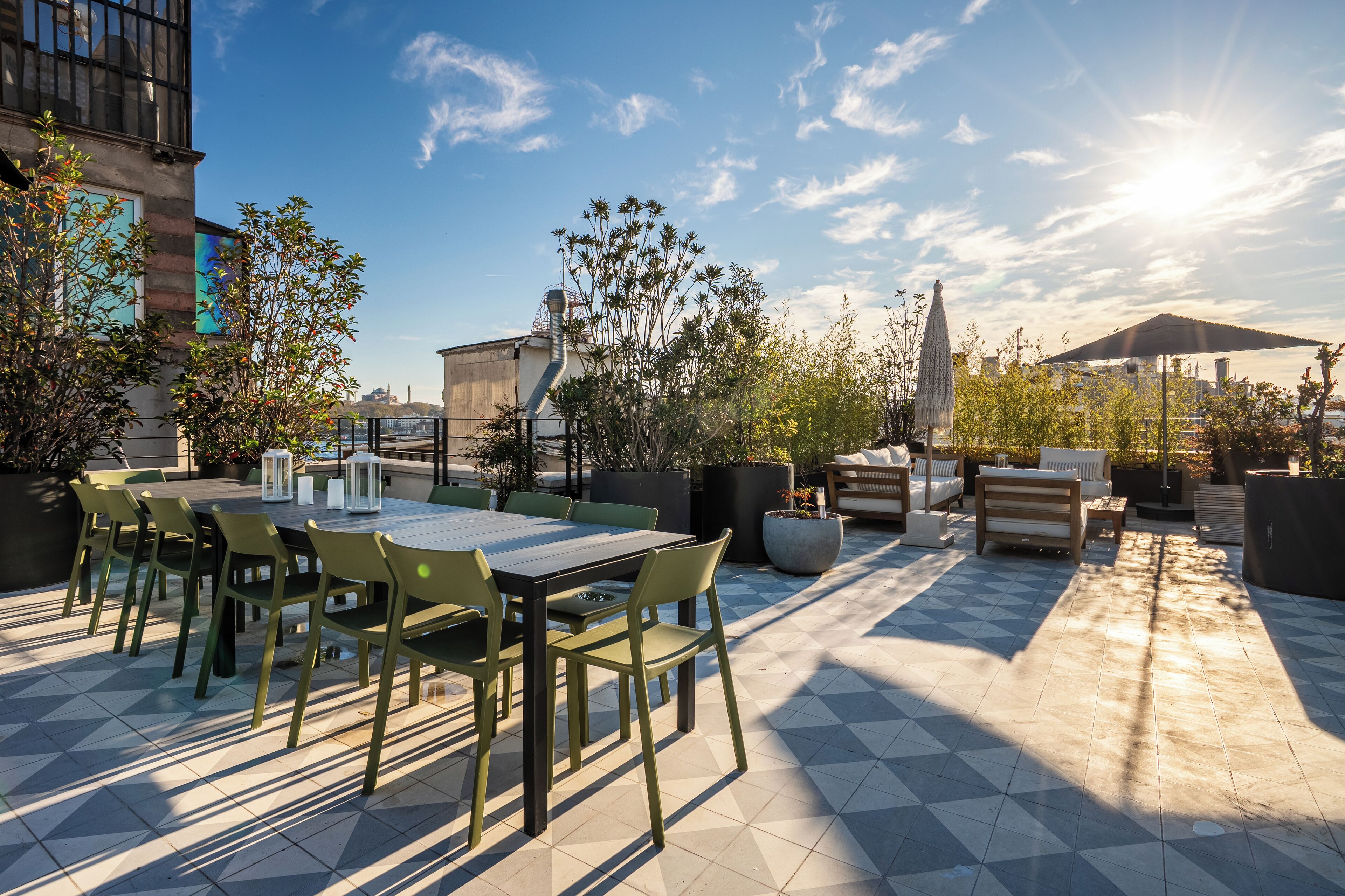 Une terrasse extérieure comprenant un espace repas, des sièges et des plantes en pot.