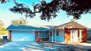 Une maison à deux étages avec un garage, une véranda et une façade en briques.