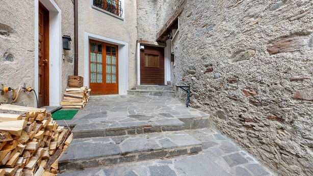 A narrow stone pathway leading to a building with wooden doors and steps.