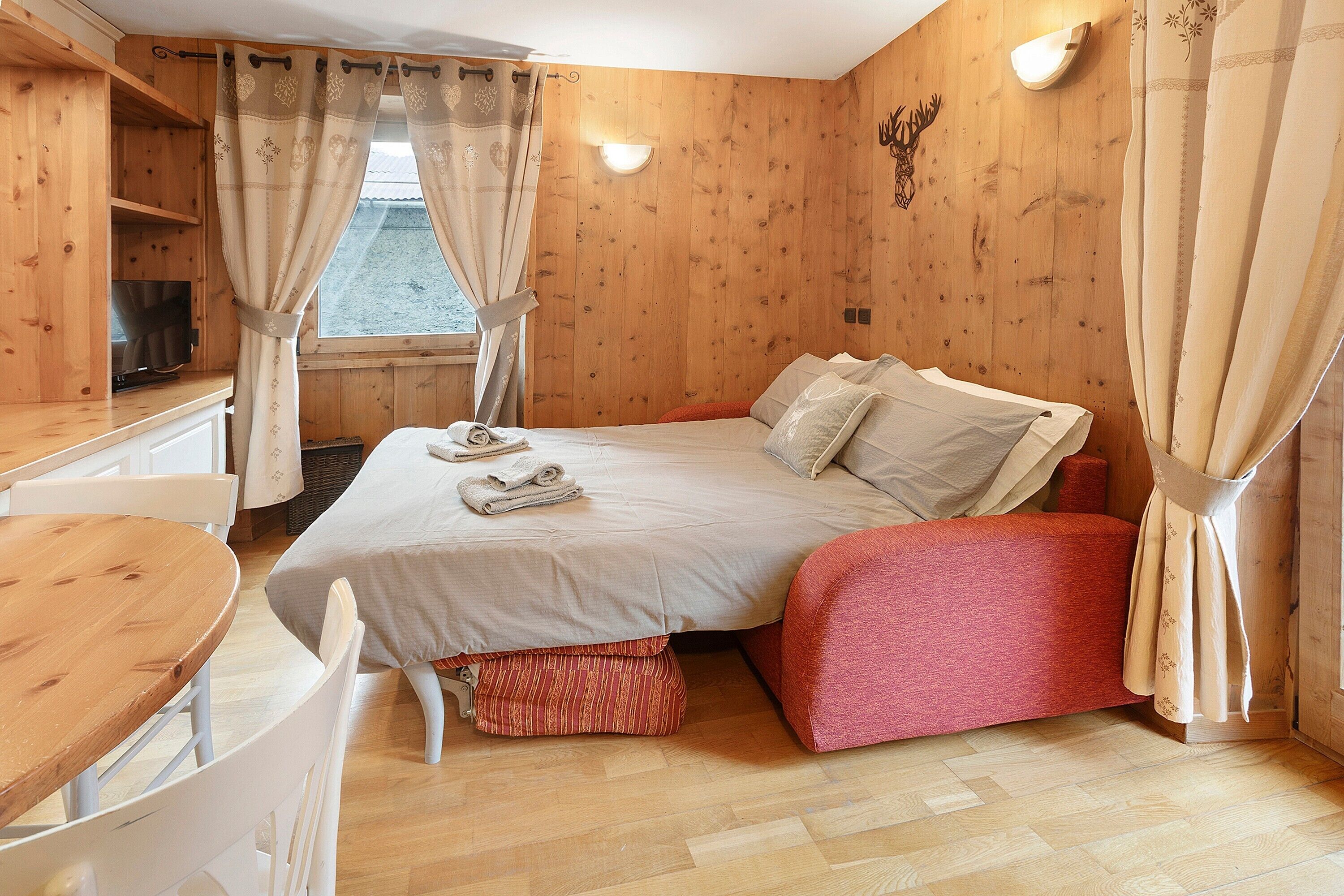 Una habitación de madera con una cama, un escritorio y una silla.