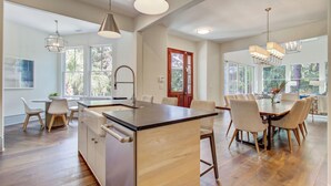 A spacious kitchen with a central island, wooden flooring, and pendant lighting. - Kiawah Exclusives | 4 Airy Hall (Kiawah Island)