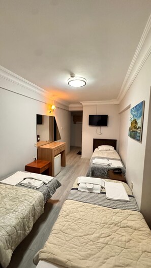A hotel room with two single beds, a desk with a chair, a TV mounted on the wall, and a painting. - HOTEL EFENDİ (Istanbul)