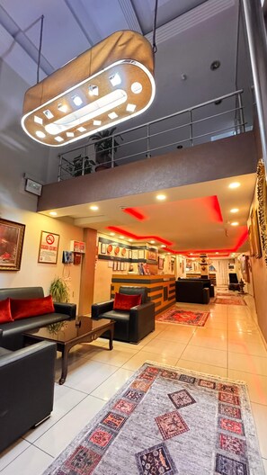 A spacious lobby with a high ceiling, a modern light fixture, a reception desk, and a staircase leading to an upper level. - HOTEL EFENDİ (Istanbul)