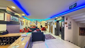 A hotel lobby with a reception desk, seating area, and a sign indicating the direction to the ACIL GIKIS. - HOTEL EFENDİ (Istanbul)