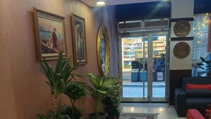 A lobby with a reception desk, potted plants, a patterned rug, and a red sofa. - HOTEL EFENDİ (Istanbul)
