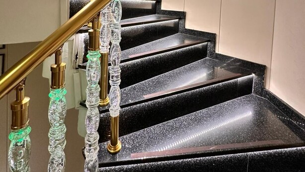 A staircase with black steps and a gold handrail, adorned with crystal-like decorations. - HOTEL EFENDİ (Istanbul)