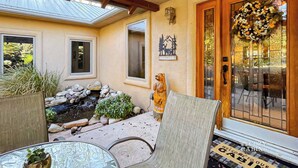 Une cabane chaleureuse avec un patio en pierre, une statue d’ours en bois et une pancarte de bienvenue.