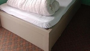 A single bed with a wooden headboard and white bedding in a room with green walls and a plaid carpet. - Hotel peace and happy (Bhimeshwar)