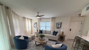 Ein Wohnzimmer mit Sofa, zwei Sesseln, einem Couchtisch und einem Deckenventilator.