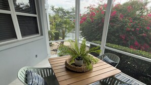Eine überdachte Terrasse mit einem Holztisch und zwei Stühlen, umgeben von einem gemusterten Teppich.