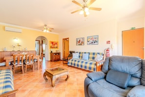 A hotel lobby with a dining area, sofas, a ceiling fan, and a fire extinguisher.