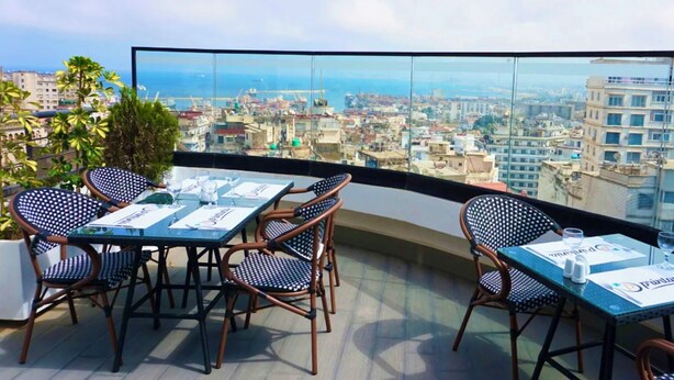 Una terrazza sul tetto con tavolo e sedie, che offre una vista panoramica sulla città.