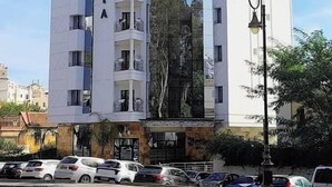 Un hotel a più piani con una facciata moderna, balconi su ogni piano e una sezione in vetro riflettente.