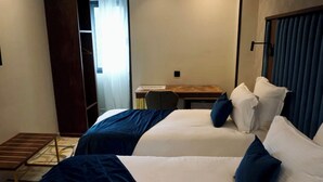 Una camera d'albergo con due letti, una scrivania e una sedia.