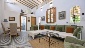 A cozy living room with a sofa, a coffee table, and a chair. There is a door leading to a bathroom. - Villa 'Valls' with Private Pool, Wi-Fi and Air Conditioning (Montuïri)
