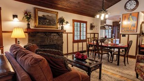 Una sala de estar acogedora con chimenea, techo de madera y un comedor con mesa y sillas.