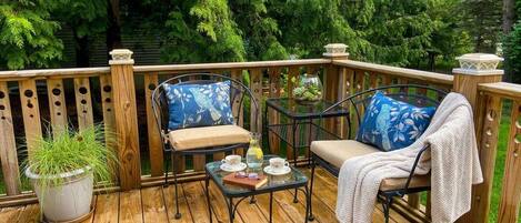 A wooden deck with two chairs and a table, surrounded by a wooden railing.