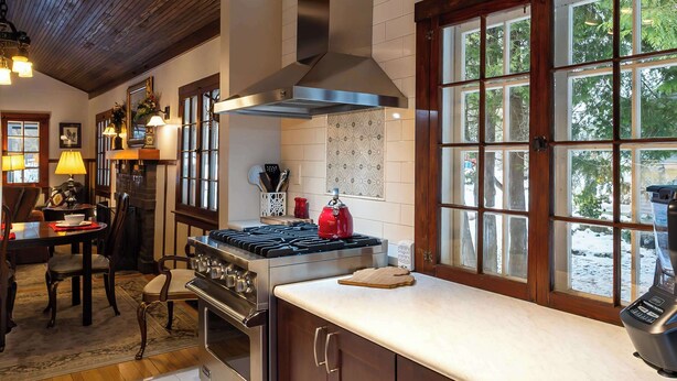 Una cocina con armarios de madera, estufa y ventana con vista a árboles.