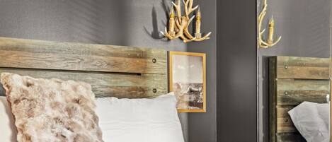 A modern bedroom with a wooden headboard, a large bed with white and brown bedding, and a framed picture on the wall.