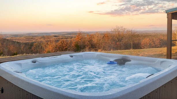 A hot tub with a wooden deck and a scenic view of a forested landscape during sunset. - Countryside Views | Sleeps 20, Hot Tub, Fire Pit (Theodosia)