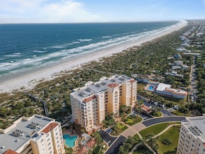 Un hotel frente al mar con varias construcciones, una playa y una piscina.