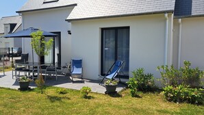 Une maison moderne dotée d’un patio, de meubles d’extérieur et de plantes en pot.