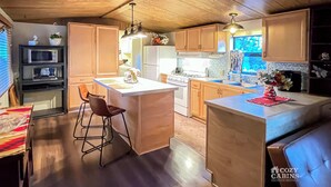 Una cocina moderna con armarios de madera, una isla central y un comedor con mesa y sillas.