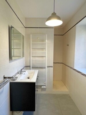 A modern bathroom with a white sink, black cabinet, and a glass shower enclosure. - Charming residence built in 1851 in Montfort (Vitrac)
