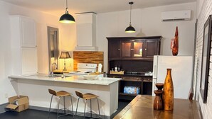 Een moderne keuken met witte kasten, een houten eiland, barkrukken en hanglampen.