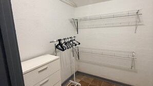 Een wasserij met een witte dressoir, een droogrek en twee draadplanken.