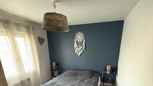 Ein Schlafzimmer mit einem Bett, einem Sessel, einem Traumfänger, einer Wandleuchte und einem Nachttisch.
