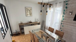 Eine moderne Küche mit Essbereich, ausgestattet mit einem Glastisch und Korbstühlen.