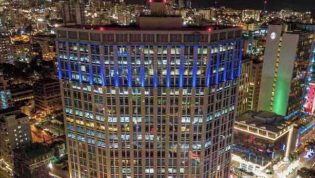 Un edificio alto con la segnaletica "ACROPOLIS", immerso in un vivace ambiente urbano di notte.