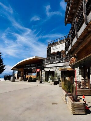 A modern building with a curved facade, outdoor seating, and a signboard. - Cosy Apartment for 5 at the Foot of the Slopes with Mountain View (Chamrousse)